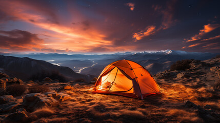 Beautiful Camping Mountain Landscape with orange Illuminated Tent at evening sunset. 