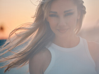 A joyous woman with flowing hair is framed by the sunset, imparting a sense of happiness and freedom