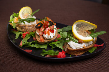 Bruschettas with cream cheese, tomatoes, olives, and lemon