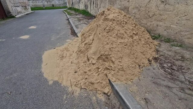 on the street lies a folded pile of sand or red clay. repair of the road of the house backfill gas power line, or reconstruction of the tennis court playground, bricklayer