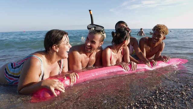 Group of friends with inflatable mat enjoying summertime at the sea. Holidays lifestyle and friendship concept.