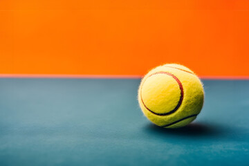 Vibrant energy on the court: A close-up of a tennis ball against a colorful background - obrazy, fototapety, plakaty