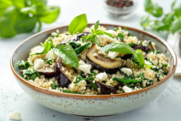 Quinoa spinach salad with eggplant and feta on white background selective focus