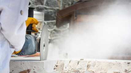 Close-up of worker cutting granite slab with grinder. Dust while grinding granite slab