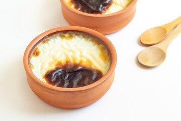 Traditional Turkish Style Baked Rice Pudding in casserole bowl,on white surface with copy space and  wooden dessert spoon