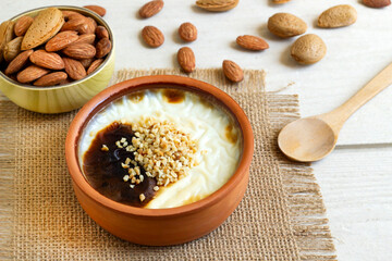 Baked rice pudding made with almond milk, with organic almonds in a casserole bowl, on a wooden surface.Vegan food