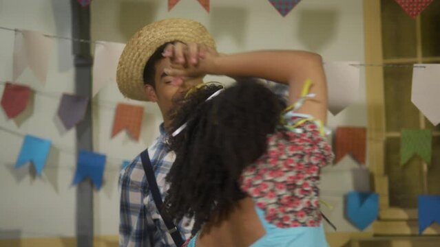 Brazilian Festa Junina, cheerful boyfriend and girlfriend dancing at event in Brazil wearing costume