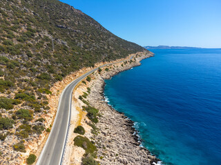View of road along coast from drone. Travelling by car in summer. Aerial view of mountain road near blue sea Beautiful landscape with highway, cliffs, sea coast