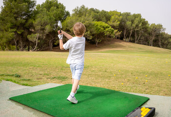 Little boy on on golf course looking after the golf ball in a shot