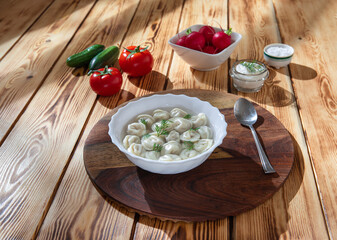 Boiled dumplings in broth, radishes, cucumbers and tomatoes on the side. 