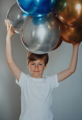 Portrait of handsome boy holding balloons above his head