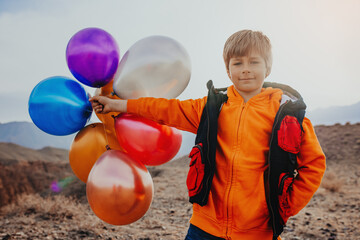 Boy hiker with balloons in the mountains