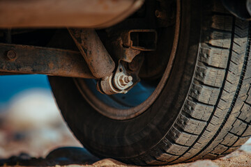 Car wheel and suspension on sand close-up view