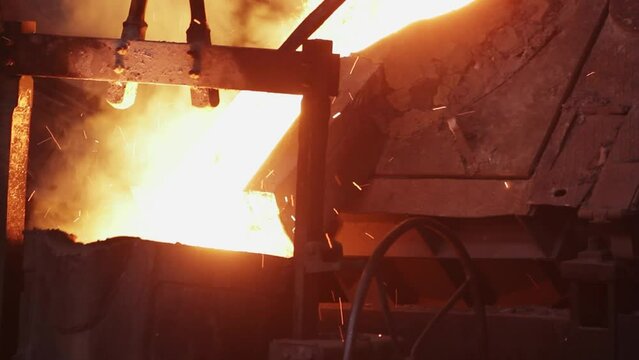 Industrial foundry steel casting, molten metal poured from ladle into mold. Heavy industry manufacturing process, extreme heat, sparks fly. Metallurgy, engineering, equipment operate in plant.