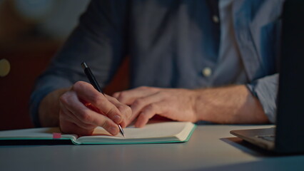 Guy arms writing pen at evening workplace closeup. Focused man making notes
