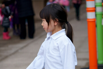 An Asian girl is waiting for her parents after school.