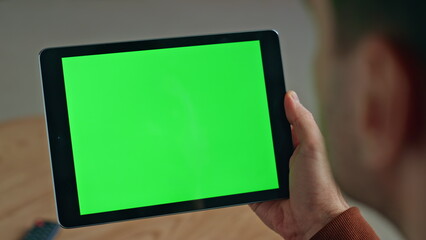 User holding chromakey computer indoors closeup. Man reading template device