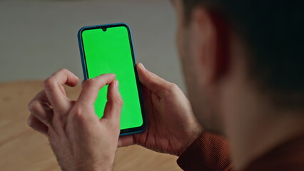 Manager fingers zooming chromakey cellphone indoors. Man working green screen