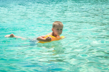 Fototapeta na wymiar A Happy child swims near the shore in flippers in the sea of travel