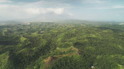 Fototapeta na wymiar Misty green rainforest mounts aerial view at Legazpi, Philippines, Asia. Heavy rain clouds at sky over Filipino mountains ranges. High Asian greenery trees and grass at soft light drone shot