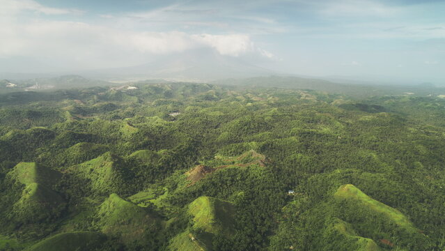 Aerial Philippines green jungle hills at Legazpi town, Asia. Tropical greenery forest with high trees, plants, grass and moss on ranges. Dusk summer day with cumulus grey clouds in dramatic shot