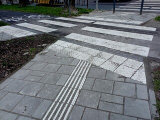 The pedestrian sidewalk intersects at the intersection with the bicycle path. Park infrastructure and bike path. Pedestrian crossing.