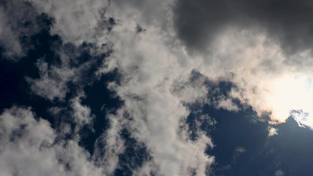 Smooth video of moving clouds and sunlight across a deep blue sky.  Cool cloud motion rolling over brilliant sun rays.