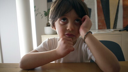 Pensive small boy pondering solution to a problem, close-up face of one handsome caucasian 5 year...