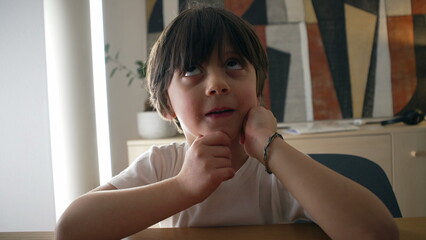 Pensive small boy pondering solution to a problem, close-up face of one handsome caucasian 5 year...