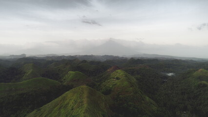 Philippines green hill aerial: mist haze over tops at volcano Mayon. Leafy tropic forest at Legazpi city, Albay province. Epic Asia nature landscape at summer cloudy day. Cinematic light soft shot