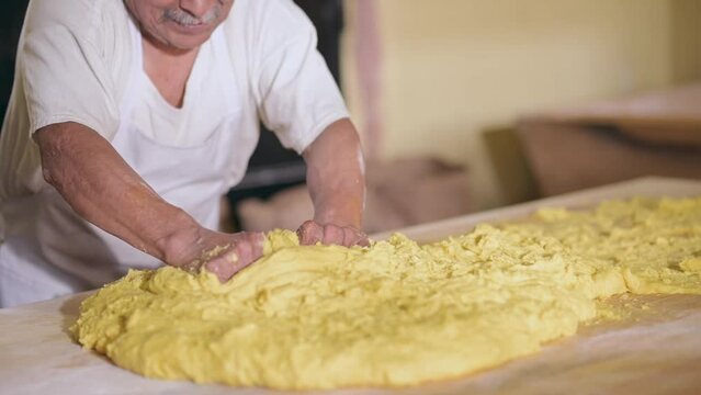 Latin man places portion of raw dough on the table to make bread.