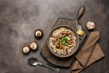 Risotto with mushrooms in a plate on a wooden cutting board, dark grunge background. Italian food....