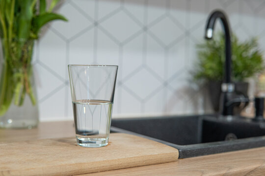 Pouring water from the tap into a glass. Hydrating with tap water, emphasizing hydration care.