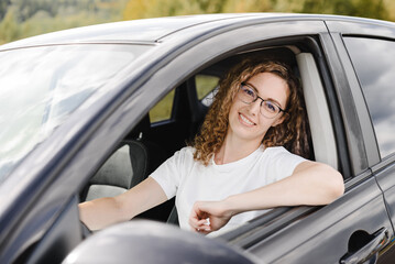 young beautiful smiling woman in car looking straight to camera, attractive caucasian woman in white t-shirt