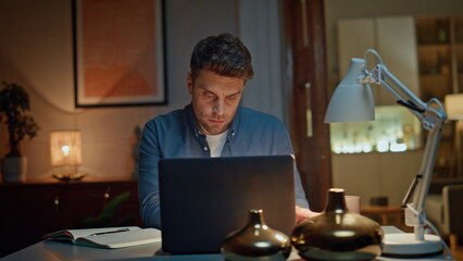 Serious worker checking phone sms in late interior closeup. Man typing laptop