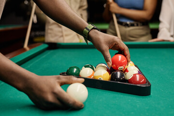 Side view closeup of hands putting billiard balls in triangle frame for pool game copy space - 782446629