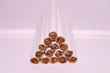 a group of white cigarettes with gold tobacco in the shape of a pyramid on a white background