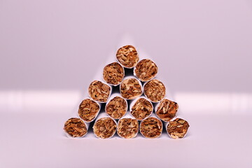 a group of white cigarettes with gold tobacco in the shape of a pyramid on a white background