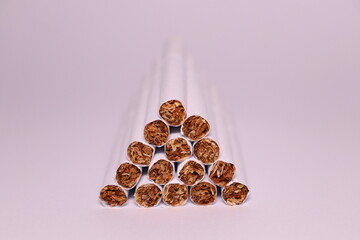 a group of white cigarettes with gold tobacco in the shape of a pyramid on a white background
