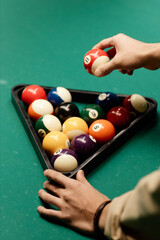 Minimal closeup of unrecognizable man holding red billiard ball while playing pool at green table copy space