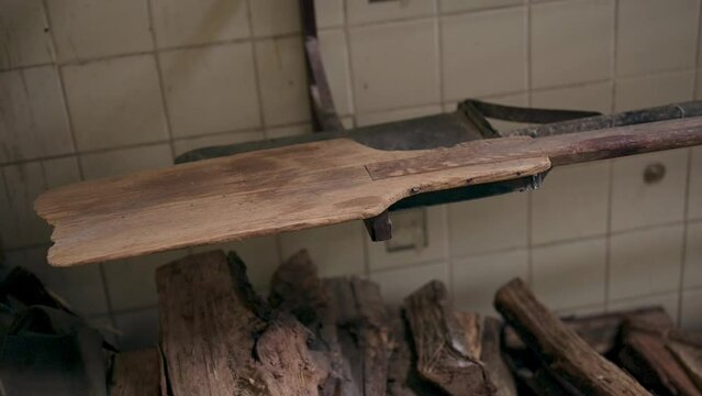 Close-up shot of the head of a wooden shovel, used to put bread in and out of a handmade industrial oven.