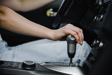 young beautiful woman driving car, close-up view of hand on gearshift lever, cropped image