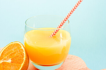 Orange lemonade with a straw in a glass. Summer orange drink with orange slice. Soda in a transparent glass. Apperol alcoholic drink. Natural juice with ice. Multivitamin freshly squeezed.