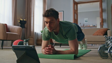Sportsman watching workout tutorial video by tablet training at home close up.