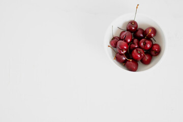 Cherries on a bowl, on white background. Minimalist composition.