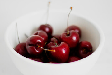Cherries on a bowl, on white background. Minimalist composition.