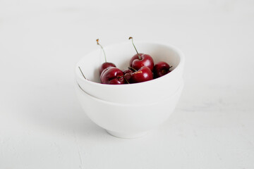 Cherries on a bowl, on white background. Minimalist composition.