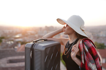 Portrait of a happy female tourist on a summer journey. young woman in straw hat with suitcase in...