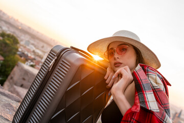 Portrait of a happy female tourist on a summer journey. young woman in straw hat with suitcase in...