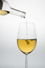 white wine glass with bottle pouring the liquid on a light background